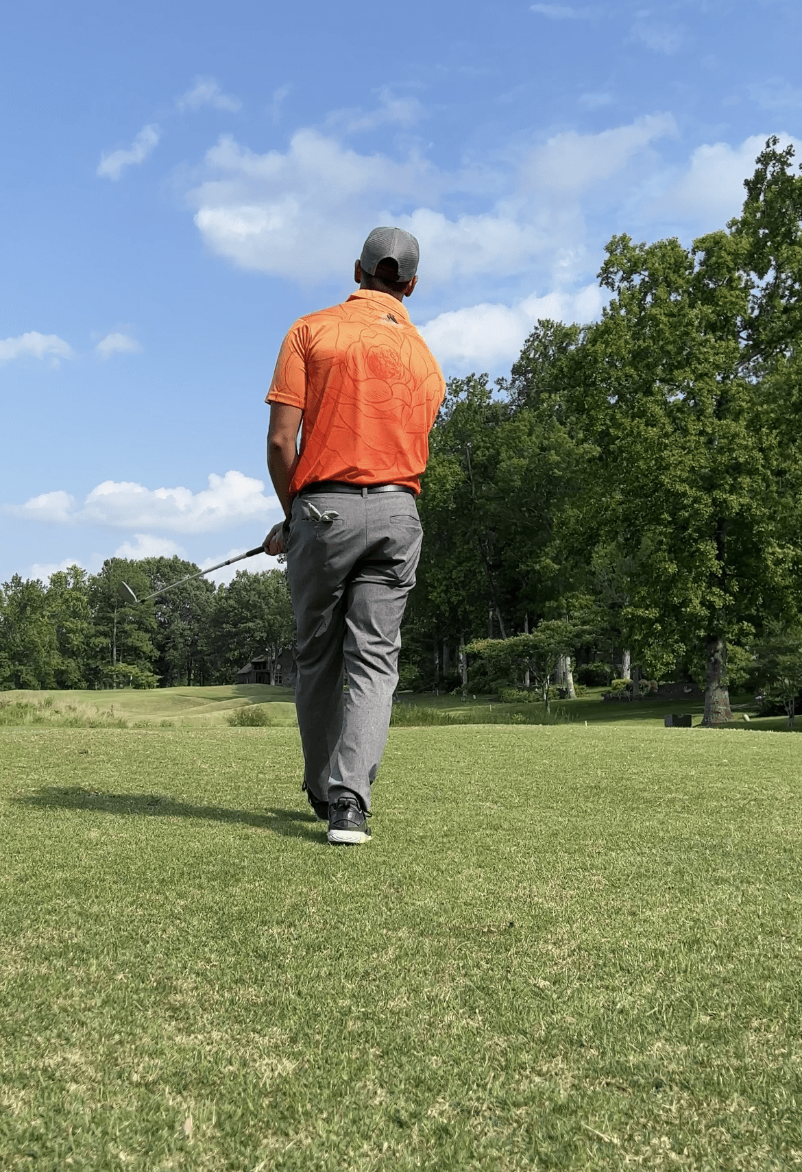 color fade orange golf shirt with floral pattern back of men's golf polo